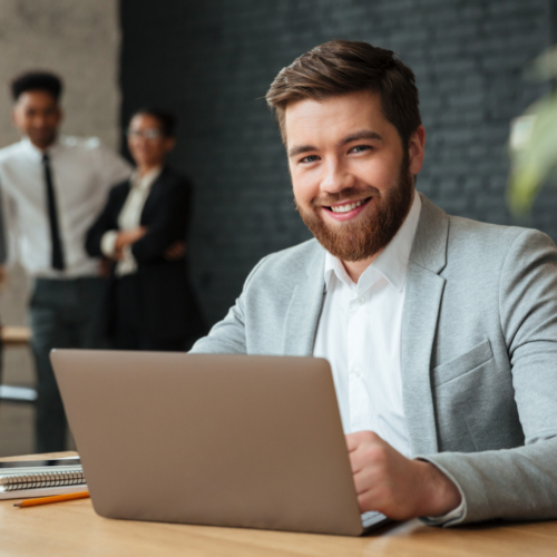 Business leader working on a laptop and managing team operations in an office environment